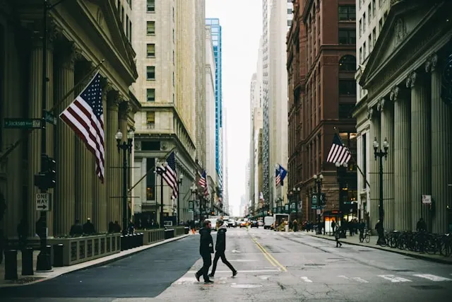 Rue du quartier financier de New York avec immeubles historiques, drapeaux américains et passants