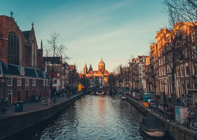 Canal d’Amsterdam bordé d’immeubles historiques, avec ponts, bateaux et piétons