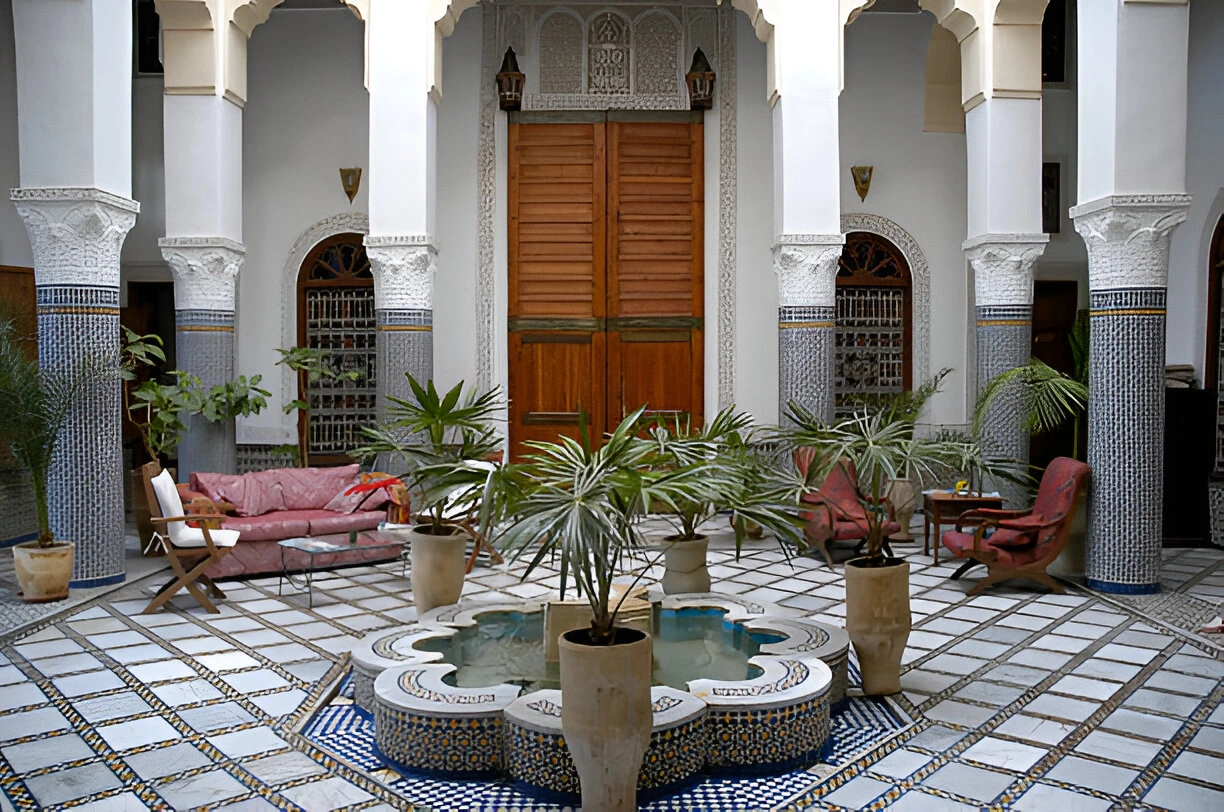 Patio of a traditional Moroccan riad with central fountain, plants and handcrafted decor