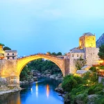 Pont Stari Most illuminé au crépuscule à Mostar, reliant les deux rives de la rivière Neretva.