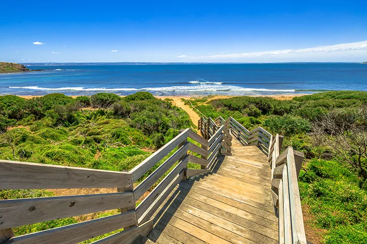 Côte de Phillip Island en Australie avec passerelle en bois et vue sur l’océan au coucher du soleil.